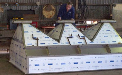 man fabriacting metal bins covered in protective sheets