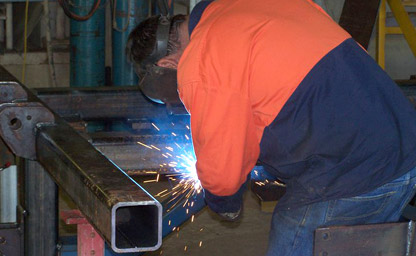 man welding steel in a large workshop